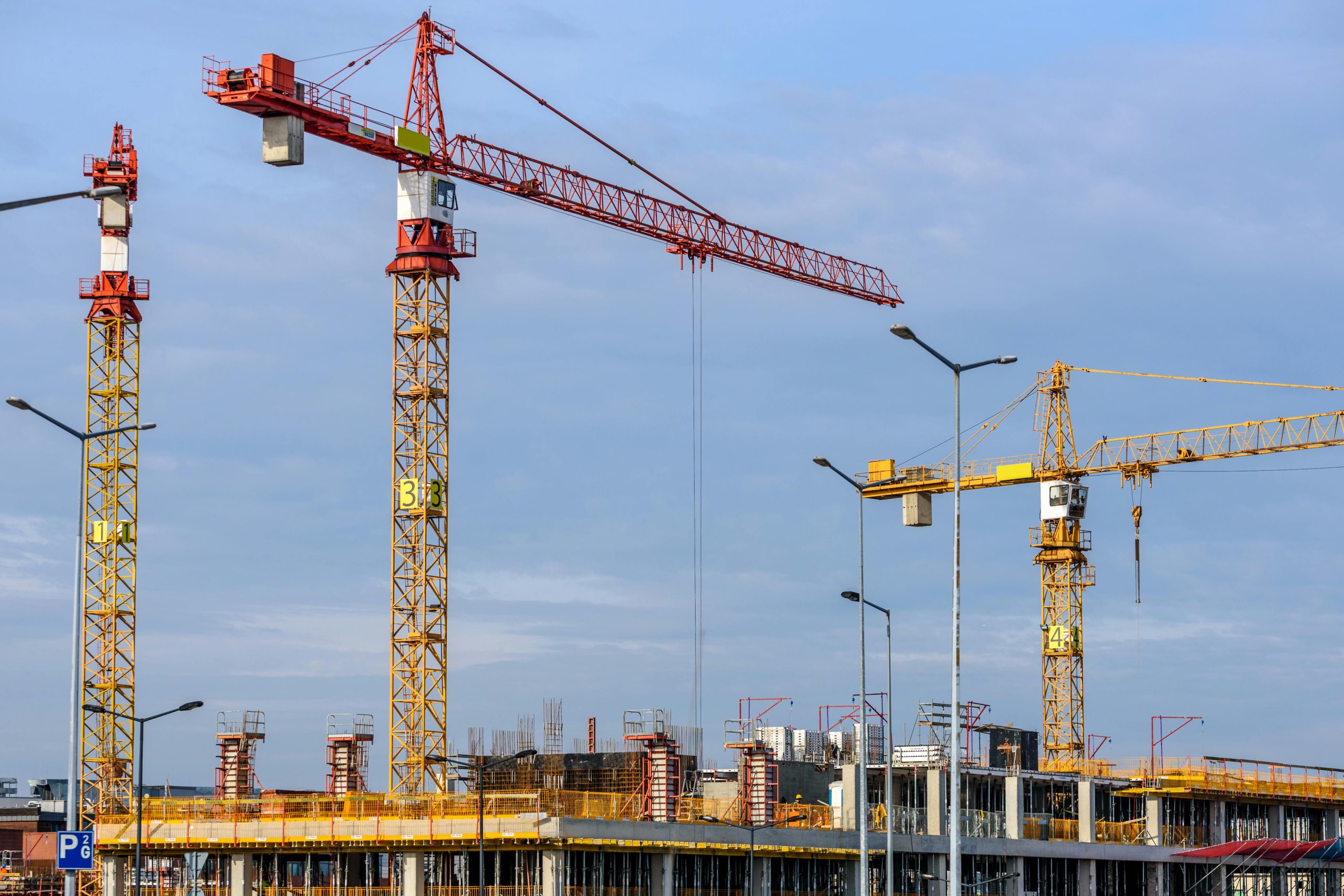 Drone surveying a construction site with workers and equipment.