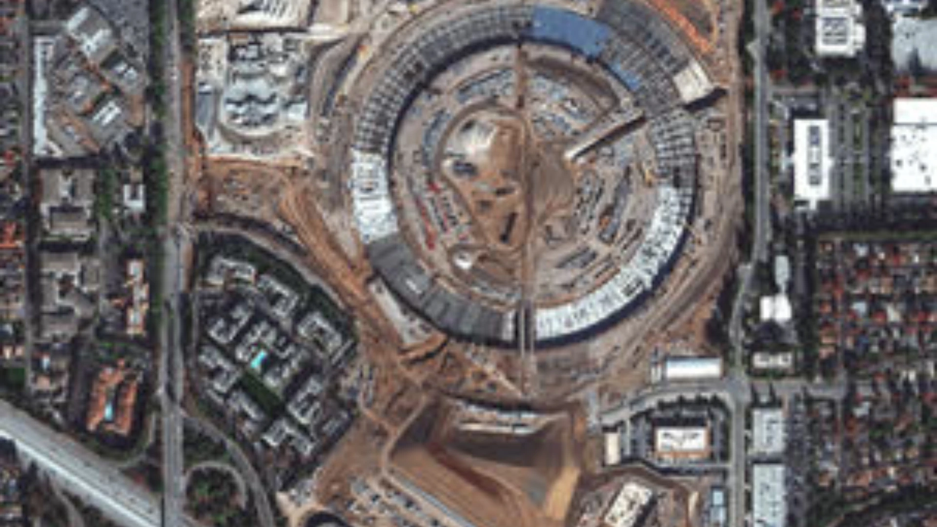 High-resolution satellite view of a construction site surrounded by dense greenery.