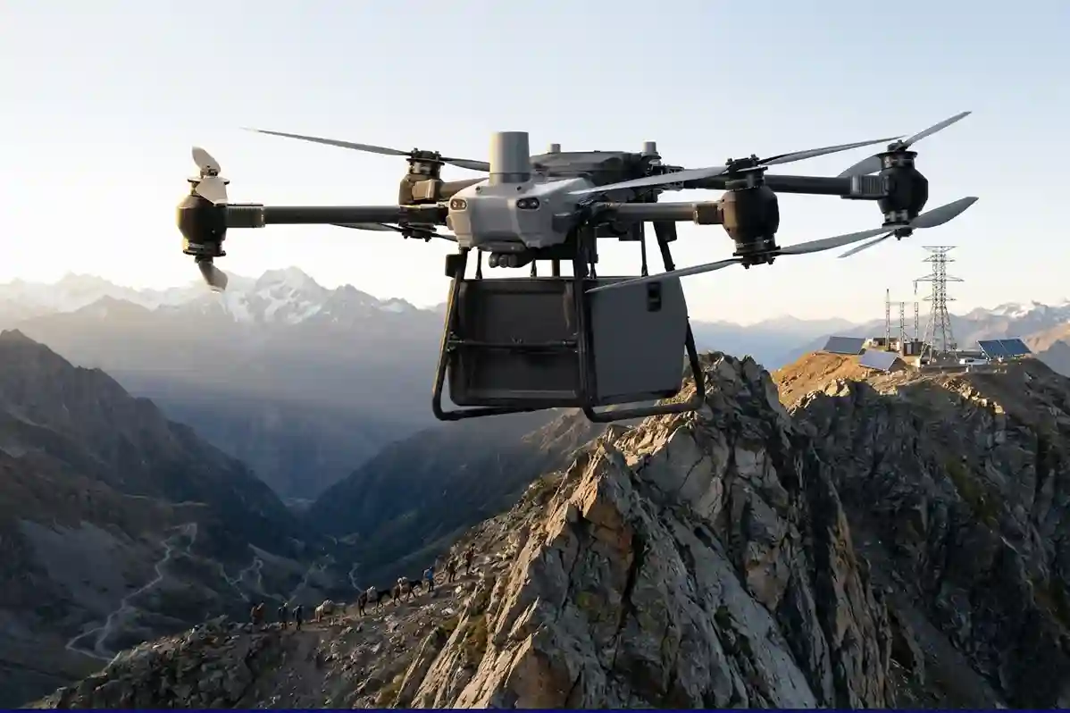 Cinematic wide shot of DJI FlyCart 30 drone carrying cargo over a steep mountain ridge toward a remote construction site.