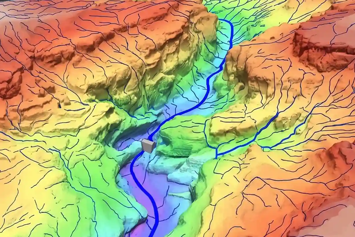 A high-fidelity 3D digital terrain model displayed on an engineering software screen, showing color-coded elevation contours and blue drainage vector lines tracing water runoff paths through dry desert valleys.
