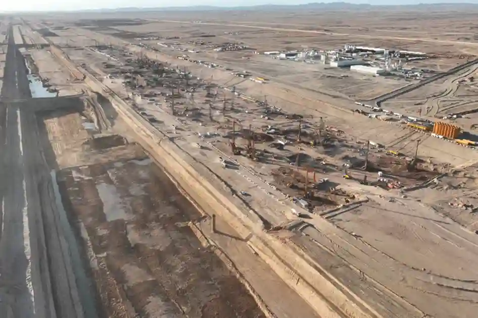 Aerial view of earthmoving fleets excavating a deep coastal trench along the Red Sea coast near rocky hills.