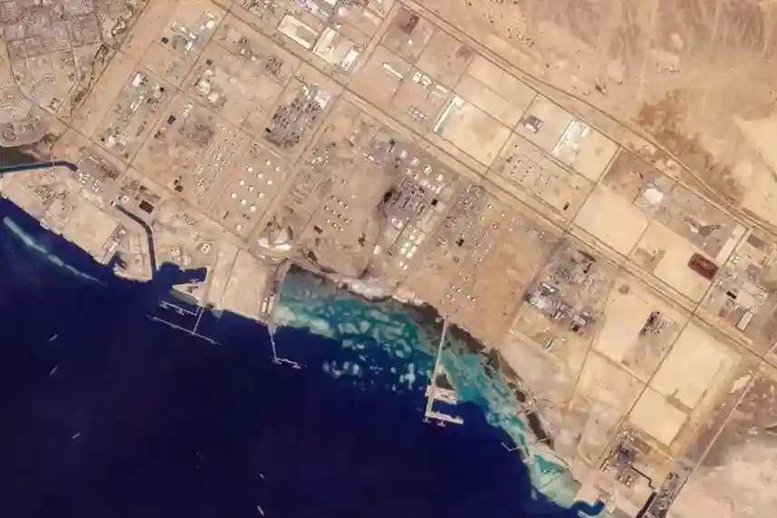 Downstream petroleum refinery in Yanbu Industrial City near the Red Sea with an aerial NDT inspection drone hovering nearby.