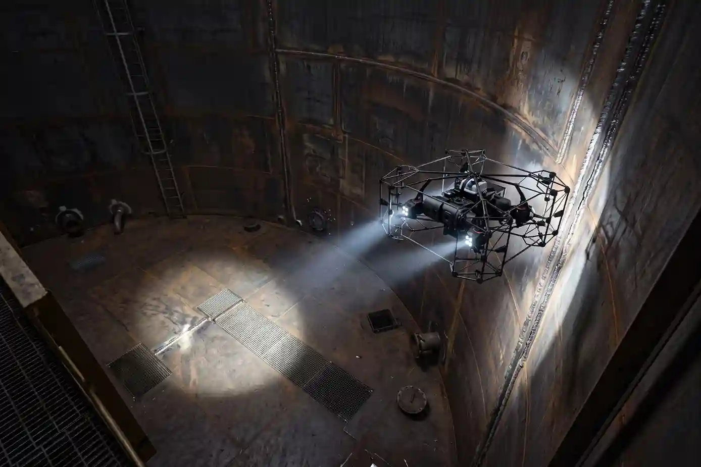 Spherical cage-protected Terra Xross 1 indoor inspection drone using LED lights inside a dark storage tank.