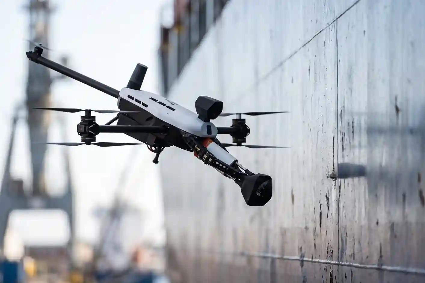 Voliro T omnidirectional NDT drone performing ultrasonic thickness testing against a vertical steel ship hull.
