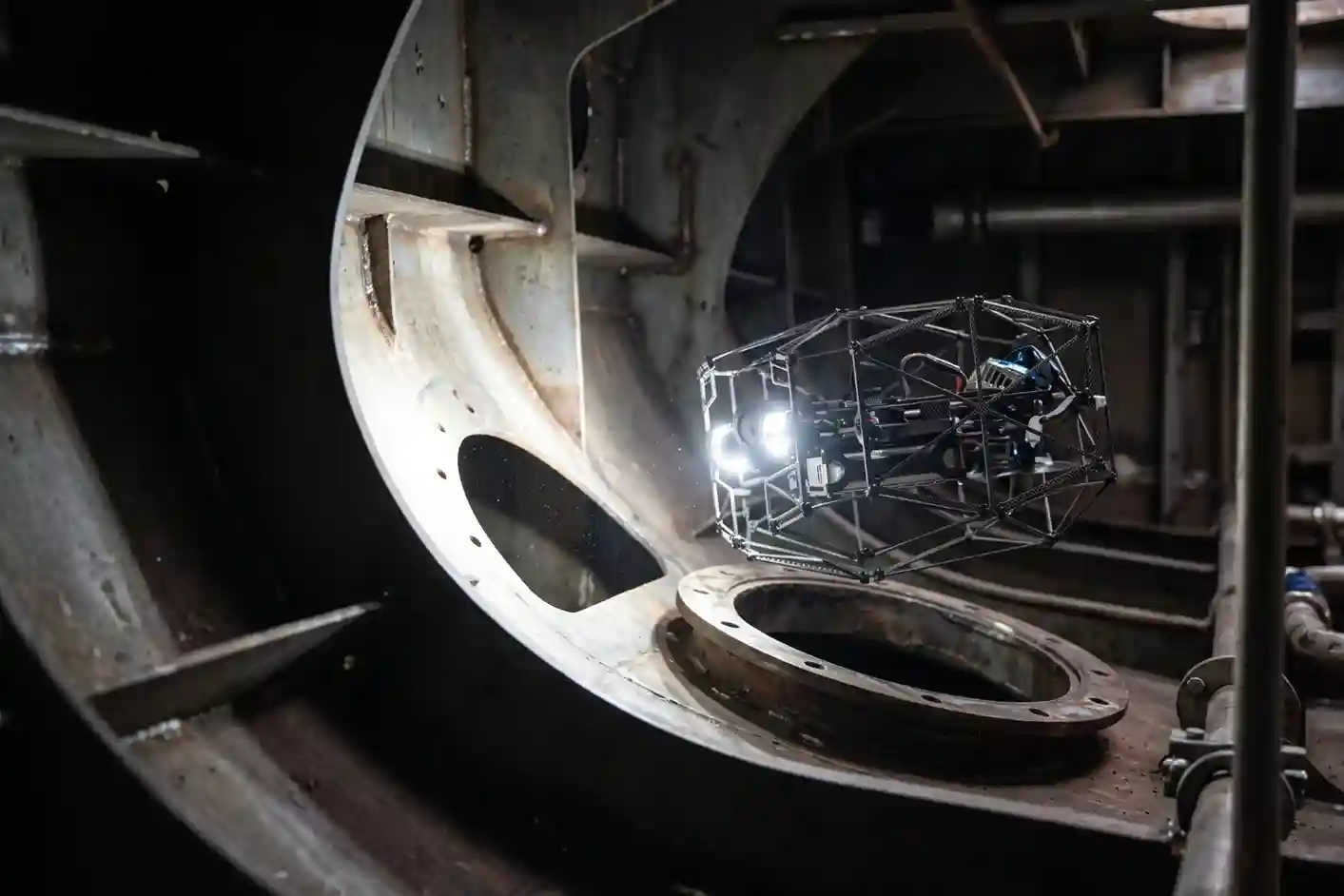 Nolvis X1 caged indoor drone inspecting internal bulkheads inside a dark ship ballast tank.
