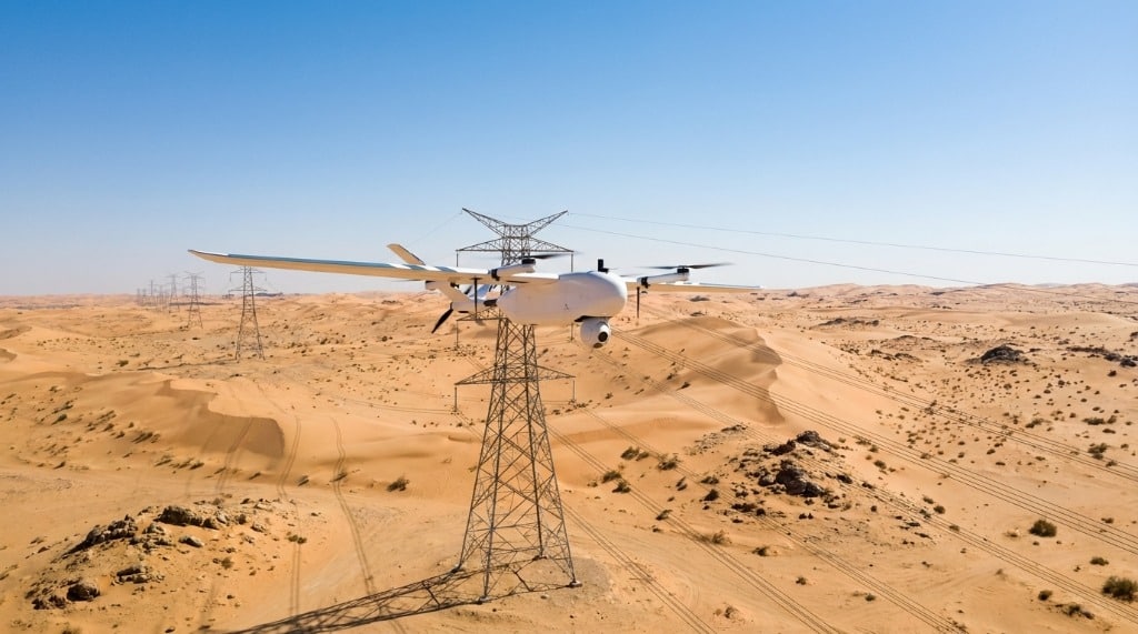 VTOL fixed-wing drone conducting long-corridor surveillance patrol along power transmission lines in Saudi Arabia